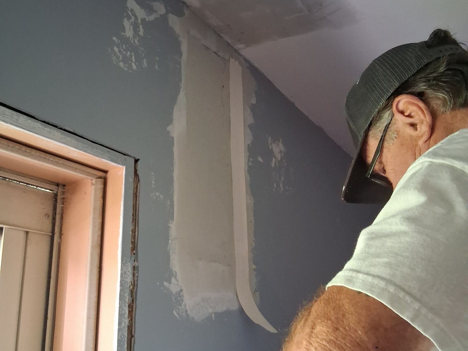 ARM Premium Painting crew member pulling drywall tape over a patched wall seam