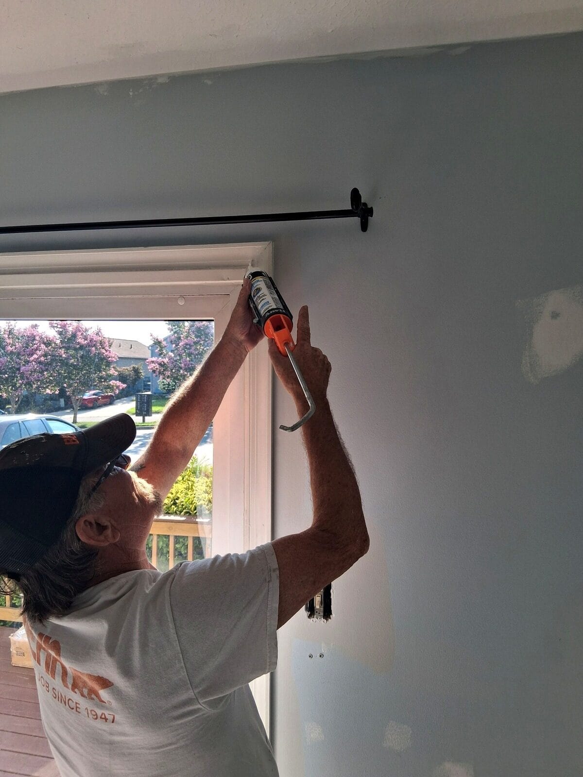 ARM Premium Painting crew member caulking window trim before painting