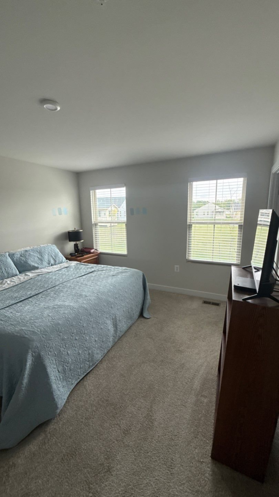 Freshly painted primary bedroom with soft gray walls and white trim