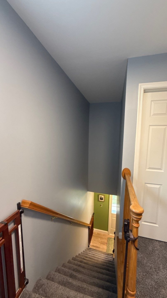 Two-story stairwell walls painted blue-gray, seen from the upper landing