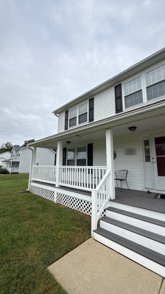 Second-story and porch-level shutters painted black on a white colonial-style home